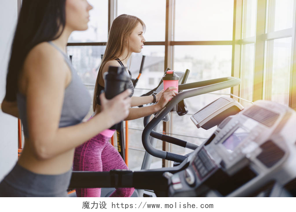 健身房里的女孩们在跑步机上健身健身房里的女孩们在跑步机上接受训练, 喝水, 面带微笑